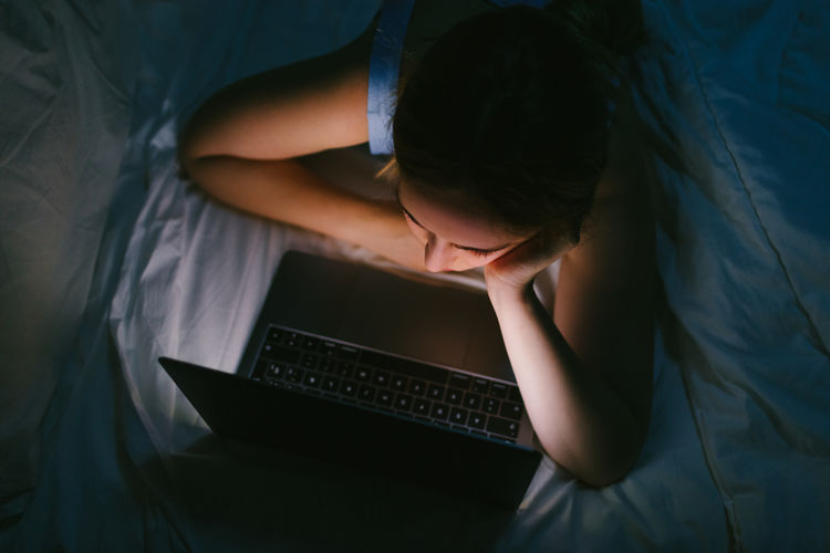 Close up view of a woman using a laptop in a bed