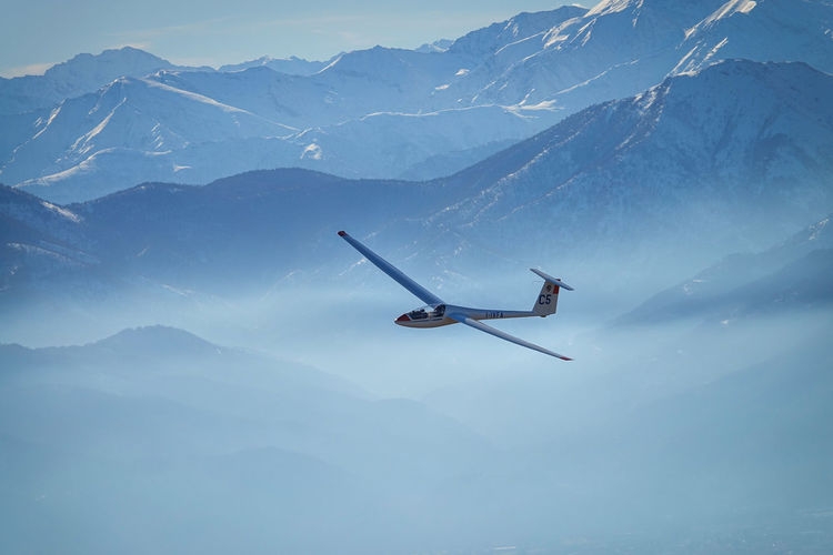 Airplane flying over snowcapped mountains against sky