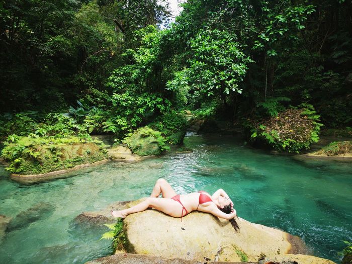 Woman lying down in water at forest