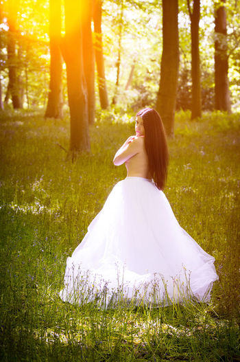 Portrait of topless young woman in long skirt standing in forest