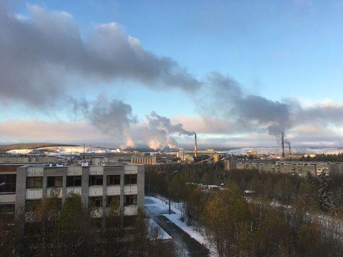 Smoke emitting from factory against sky