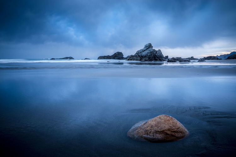 Scenic view of mountain on shore against sky