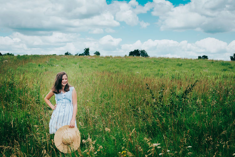 Girl holding a sun hat standing in a field