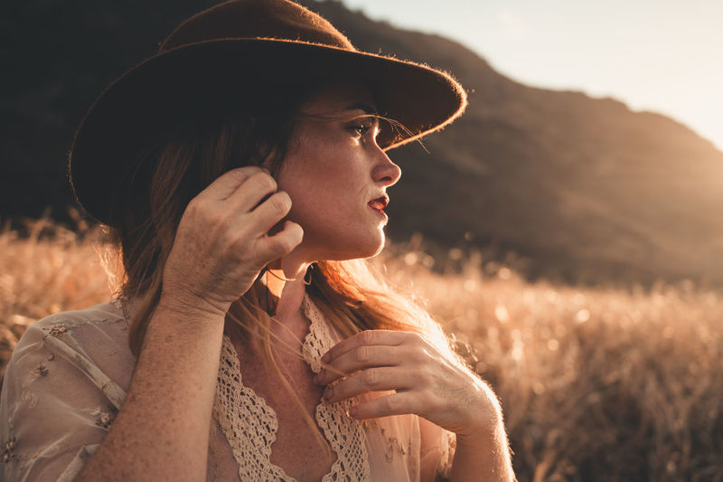 Portrait of woman wearing hat standing on field