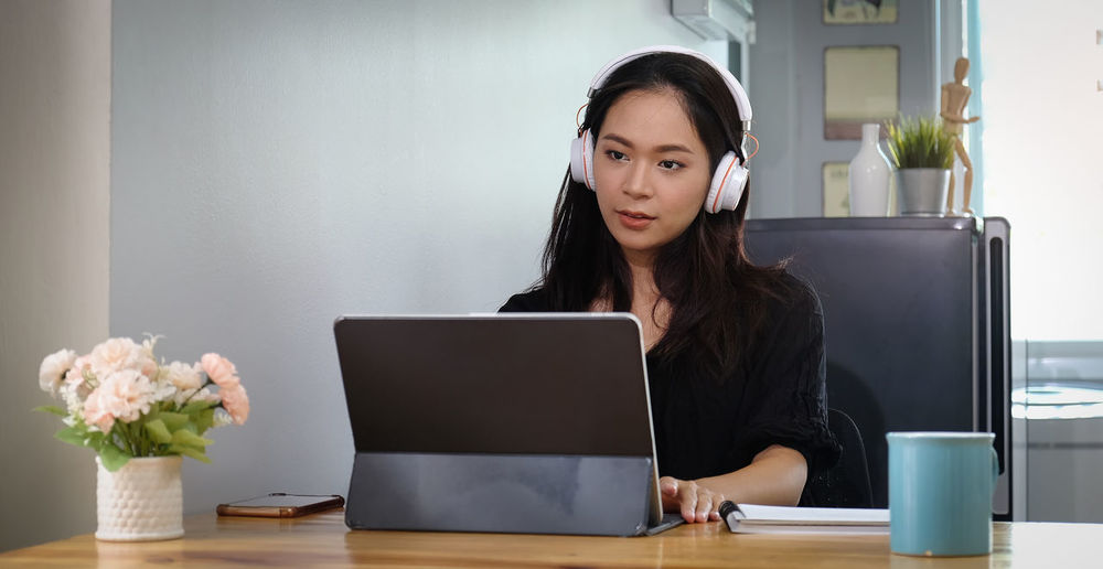 Businesswoman using laptop while wearing headphones