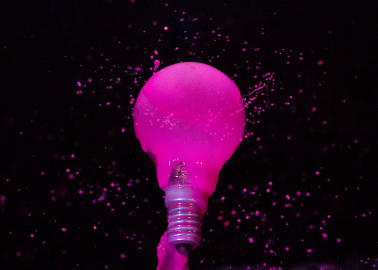 Close-up of electric bulb with pink liquid against black background