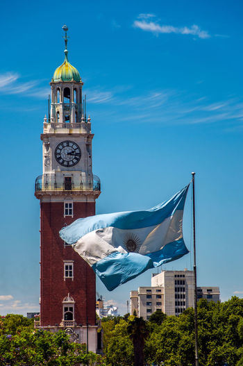 Argentinian flag waving in front of torre monumental against sky