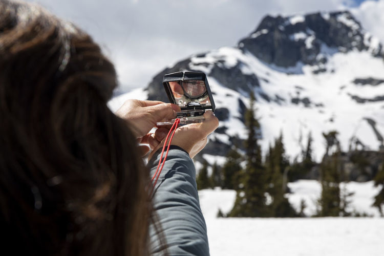 Rear view of woman photographing on snowcapped mountain