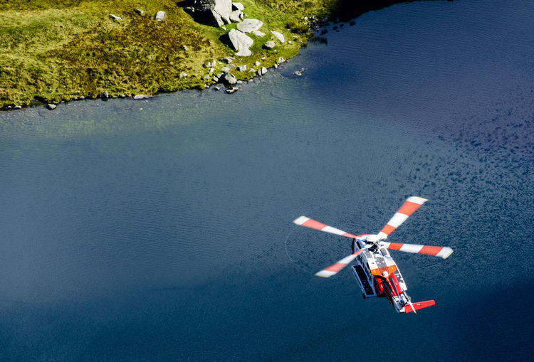High angle view of rescue helicopter flying over lake at snowdonia national park