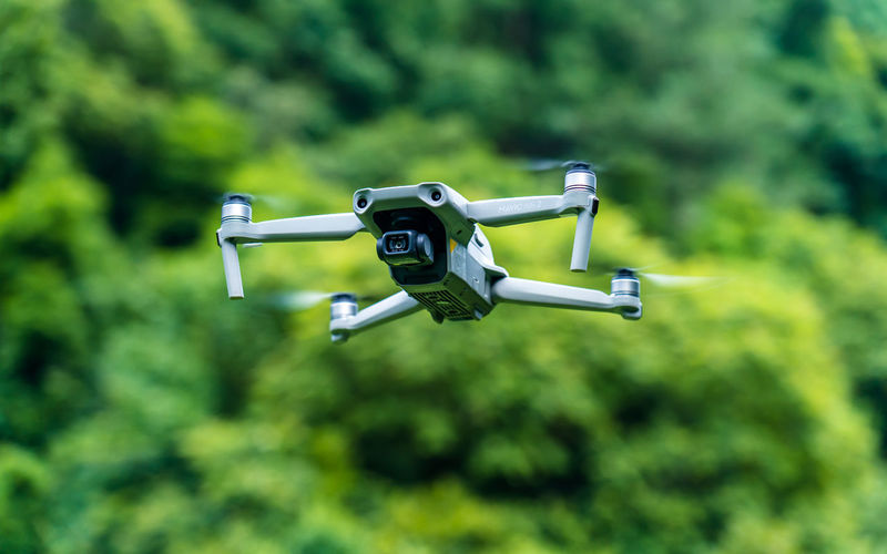 Close-up of drone flying against trees