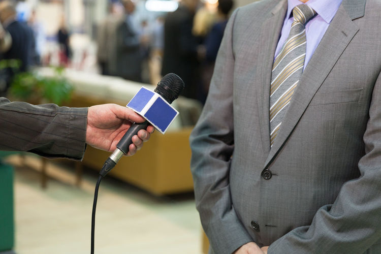 Cropped hand of journalists interviewing man