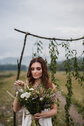 Bride holding bouquet while standing on field