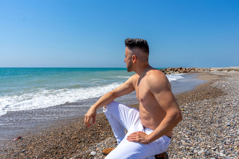 Man sitting on beach against sea