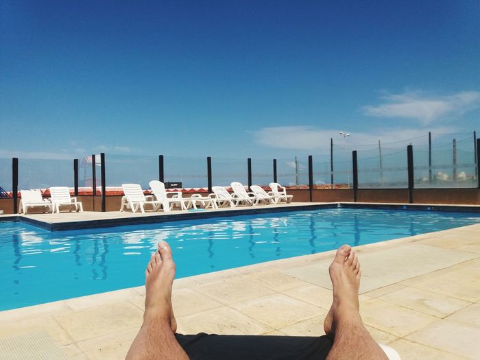  relaxing in swimming pool against blue sky