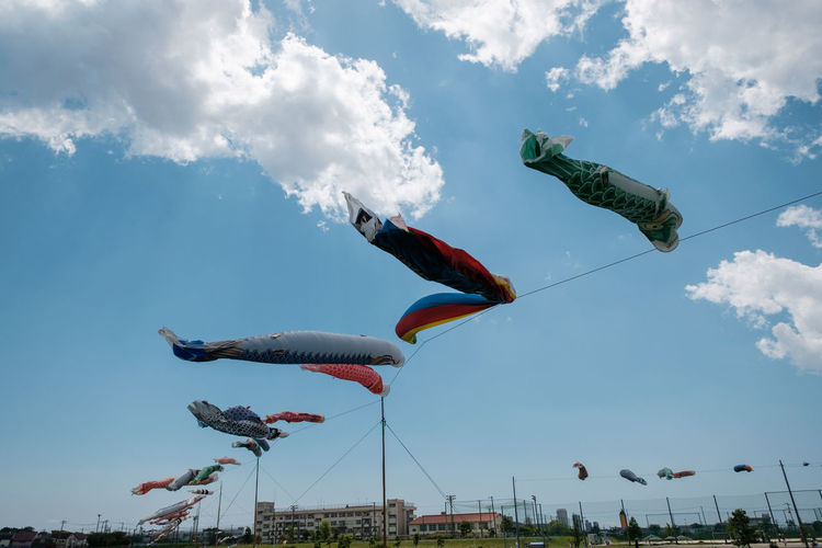 Low angle view of kites flying against sky
