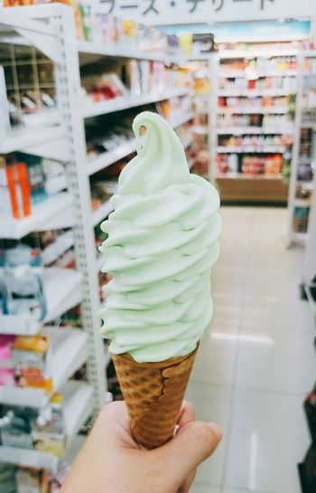 Cropped hand holding ice cream cone at store