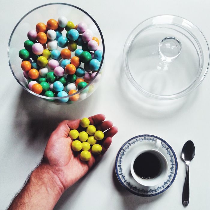 Cropped image of man with gumballs and black coffee on table at home