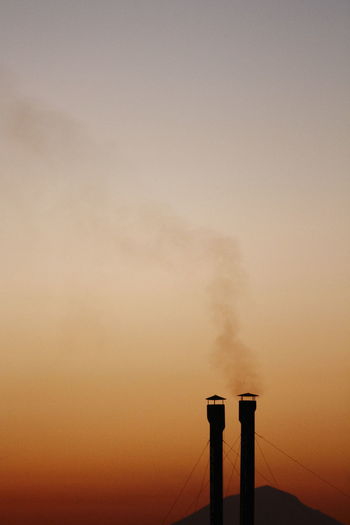 Smoke emitting from chimney against sky at sunset