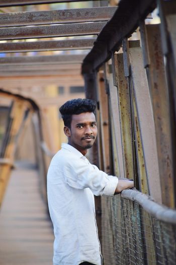 Portrait of young man standing on footbridge