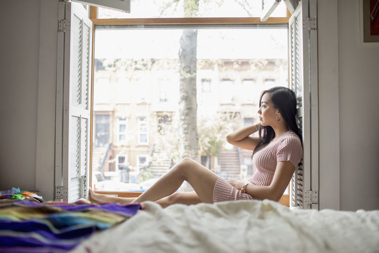 Young woman sitting on a windowsill
