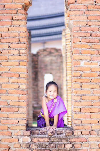 Portrait of girl standing against brick wall