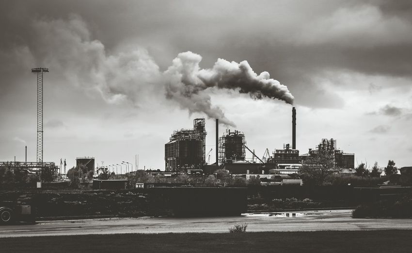 Smoke emitting from factory against sky