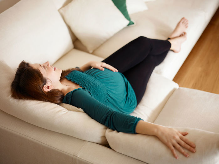 High angle view of woman lying on sofa at home