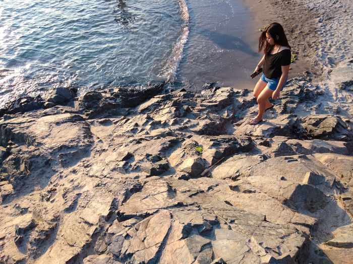 Full length of woman walking on rock at beach