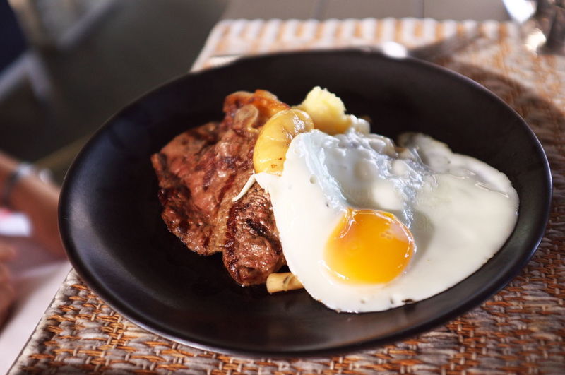 High angle view of fried egg and steak in plate on table