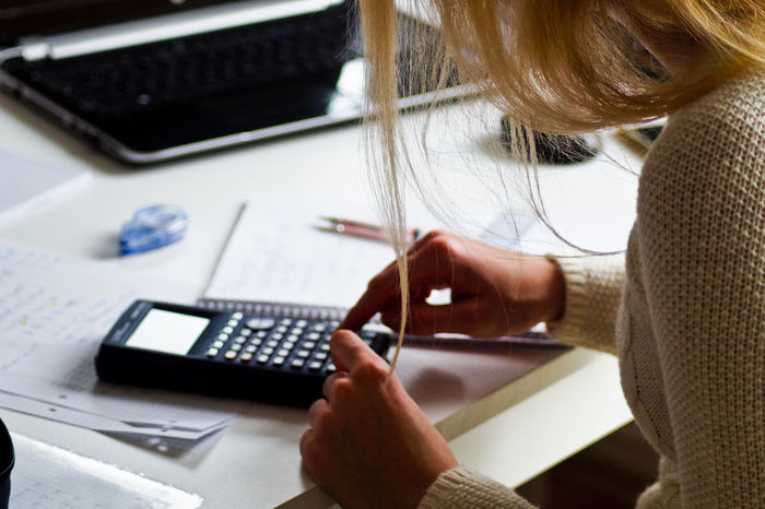 Midsection of woman using calculator while sitting at desk