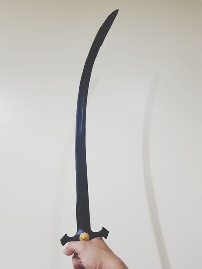 Close-up of person holding sword against white background