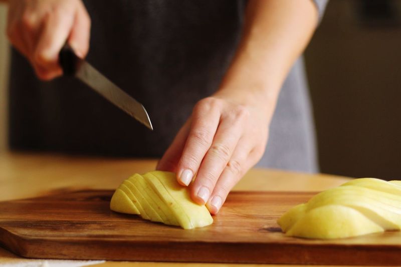 Midsection of woman chopping potatoes on cutting board in kitchen