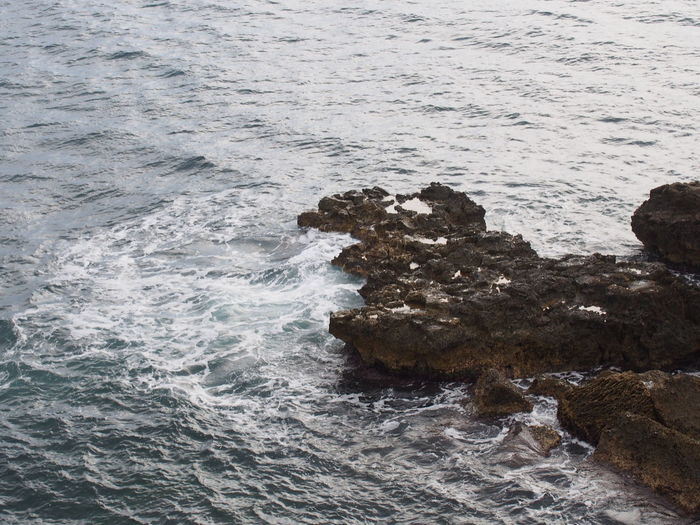 High angle view of waves splashing on rocks at beach