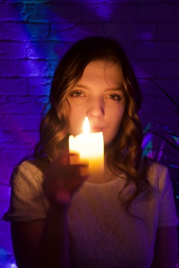Portrait of young woman holding illuminated candles