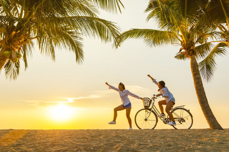 People riding bicycle on beach during sunset