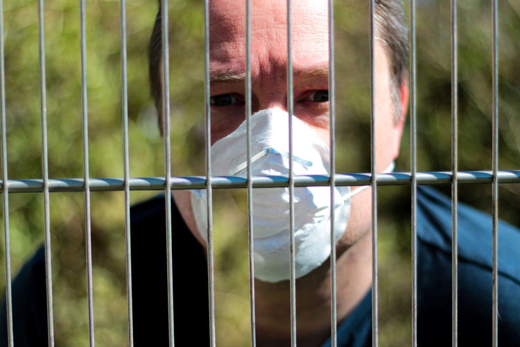 Portrait of man seen through metal fence