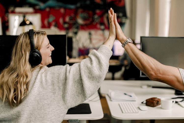 Smiling entrepreneurs giving high-five at workplace