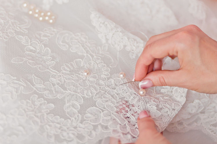 Close-up of cropped hands sewing wedding dress