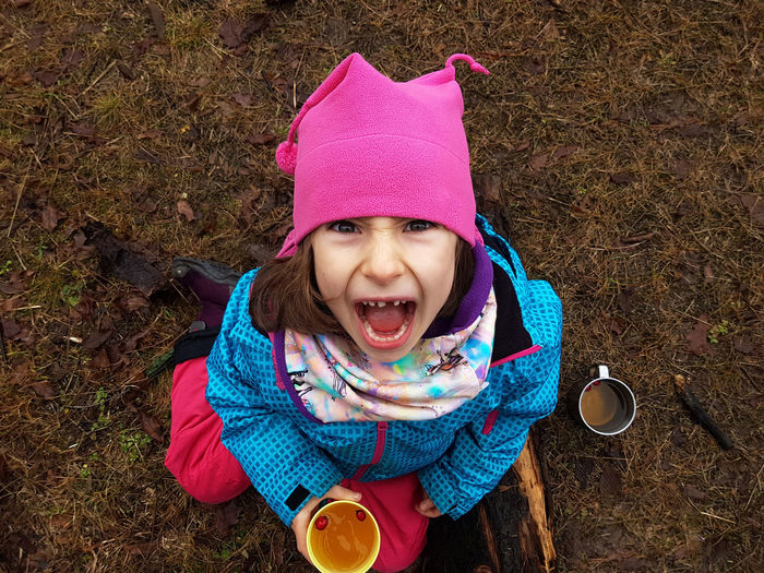 Trekking kid drinking hawthorn tea and making a grimace in the outdoors