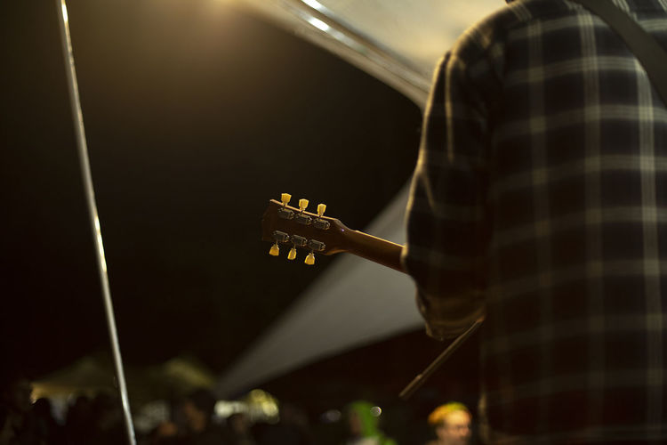 Guitarist holds guitar. performance of musician at festival. reggae music outside. person