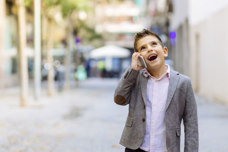 Boy talking over smart phone while standing in city