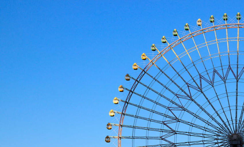 High section of cropped ferris wheel against clear blue sky