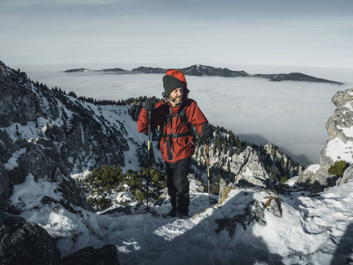 Germany, bavaria, ammergau alps, teufelstattkopf, tourist hiking in mountains on winter day