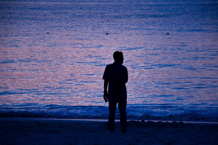 Rear view of silhouette man standing at beach