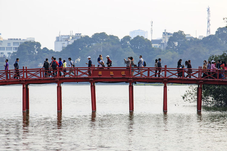 Scenic view of people on footbridge in city