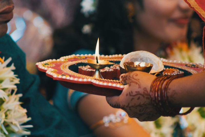 Cropped hand of woman holding diya in plate
