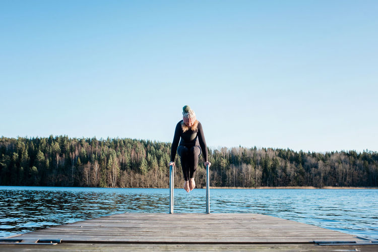 Woman balancing on steps preparing for cold water swimming in sweden