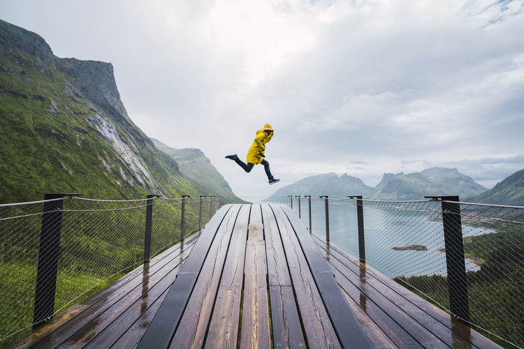 Norway, senja island, man jumping on an observation deck at the coast