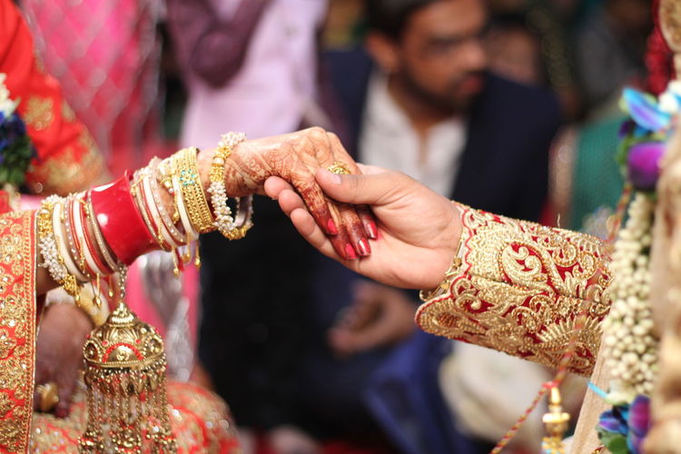 Cropped image of bride and bridegroom holding hands