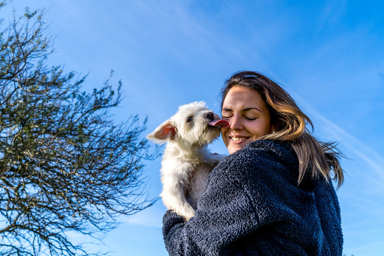 Young girl plays with her white dog in sunny day